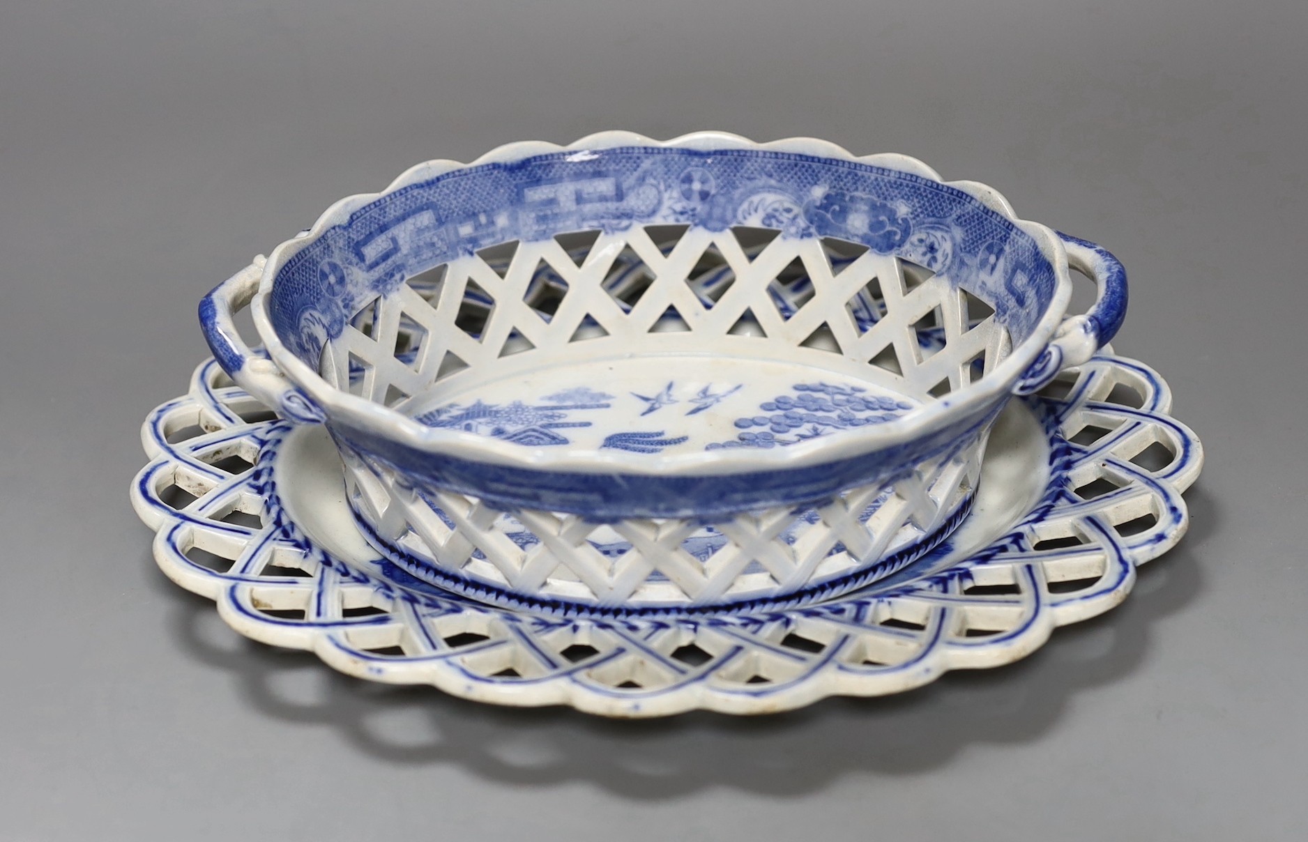 An early 19th century English blue and white pearl ware oval two handled chestnut reticulated basket with transfer printed chinoiserie decoration, together with a similar oval stand